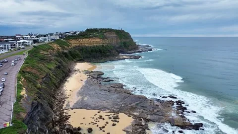 Bar Beach aerial pull away shot with rolling waves and cloudy skies. Stock Footage 313871692