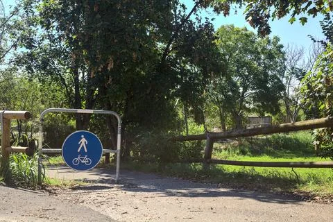 Bar with a blue sign at the beginning of a path bordered by trees in the ital Stock Photos
