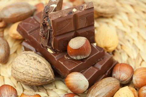 Bar of chocolate and nuts on a wicker mat Stock Photos