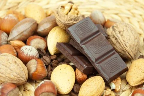 Bar of chocolate and nuts on a wicker mat 스톡 사진