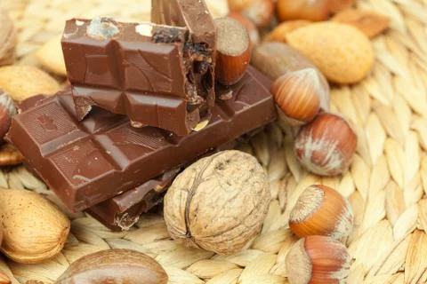 Bar of chocolate and nuts on a wicker mat Stock Photos