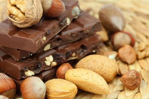 Bar of chocolate and nuts on a wicker mat Stock-Fotos