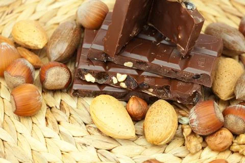 Bar of chocolate and nuts on a wicker mat Stock Photos