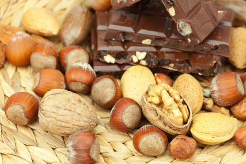 Bar of chocolate and nuts on a wicker mat Stock Photos