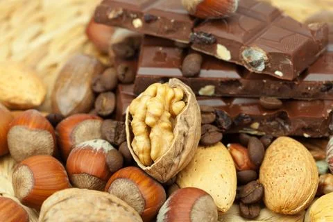 Bar of chocolate and nuts on a wicker mat Stock Photos