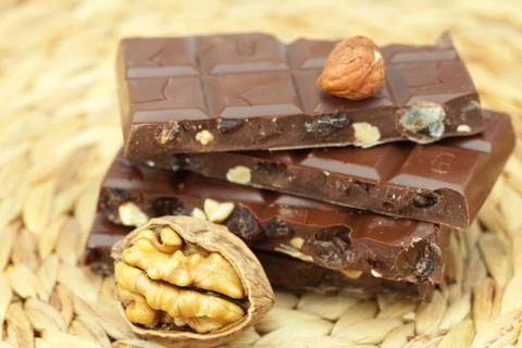 Bar of chocolate and nuts on a wicker mat Stock Photos