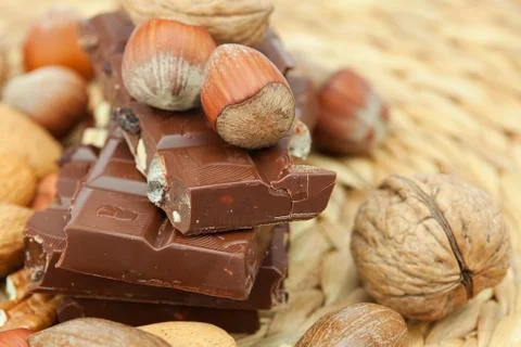 Bar of chocolate and nuts on a wicker mat Stock Photos