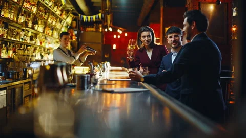 Bar clients sharing drinks celebrating Friday at evening. Friends enjoying party Stock Footage 319794564