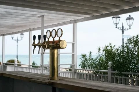 Bar counter with beer column with three taps in the beach bar on the backgrou Stock Photos