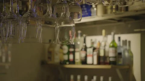 Bar Glasses Hanging Above Counter with Bottles on Shelves in Beijing Bar Stock Footage 345751745