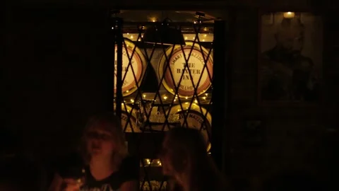 Bar Patrons Drinking in Dimly Lit Sydney Venue with Wooden Barrels and Warm Stock Footage 345691175