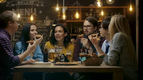 In the Bar/ Restaurant Group of Diverse Young People Eat Slices of Pizza Pie.  Stock Footage 83678447