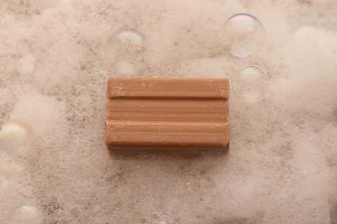 Bar of soap resting on soft bubbles in a warm bath environment during a relaxing Stock Photos