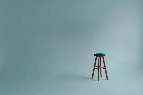 Bar stool with upholstered backless seat in an empty white room on a gray bac Stock Photos