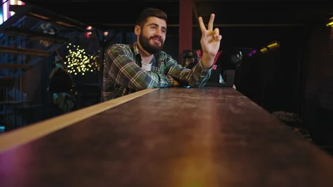 On a bar table good looking guy smiling and happy ordering a glass of drink Stock Footage 135911909