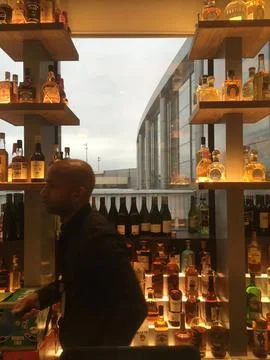Bar tender walks passed window overlooking the runway at a bar in JFK airport. Stock Photos