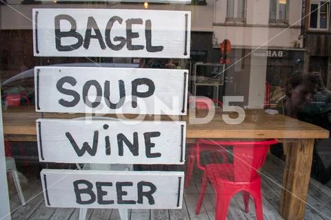 Bar window with handwritten sign panels advertising bagel, soup, wine and bee Stock Photos
