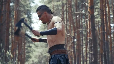 Barbarian warrior throws his axes on the ground and climbs on a tree Stock Footage 138423745