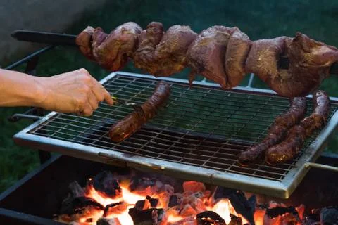 Barbecue with beef inserted in a sword and some sausages on a grill grilling Foto stock
