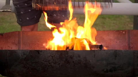 Barbecue grid heated on wood fire flames and scrubbed with steel brush to clean Stock Footage 335457214