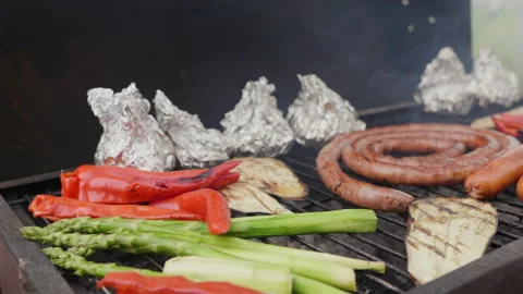 Barbecue with Grill man's hand opens sausages and vegetables outdoors Stock Footage 232136413