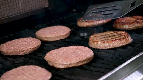 Barbecue for a hamburger cooked on an open fire and turned over meat patties Stock Footage 257003304