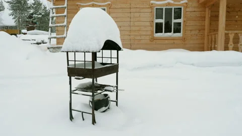 Barbecue or brazier standing in front of a wooden house on a snowy winter day. 動画素材 130439975