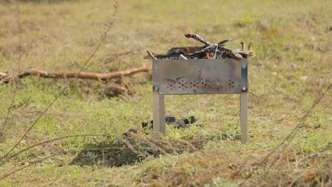 Barbecue in which the fire burns, stands on the green grass. Video stock 127934793