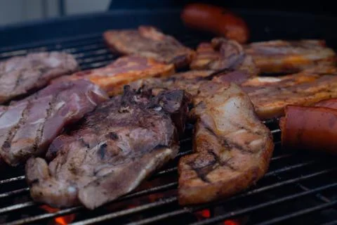 Barbecuing meat on a grill Stock Photos