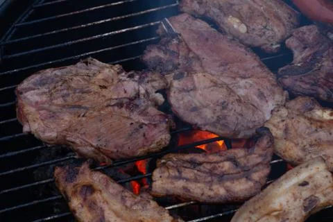 Barbecuing meat on a grill Stock Photos
