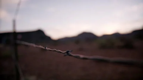 Barbed wire against beautiful sunset and mountains in the desert Stock Footage 154912098