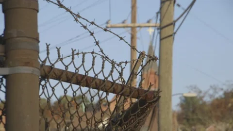 Barbed wire and chain link fence, powerlines and church in background Stock Footage 304373261