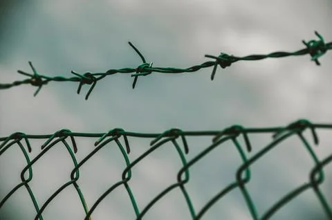 Barbed wire and chain link fence creating boundaries Stock Photos