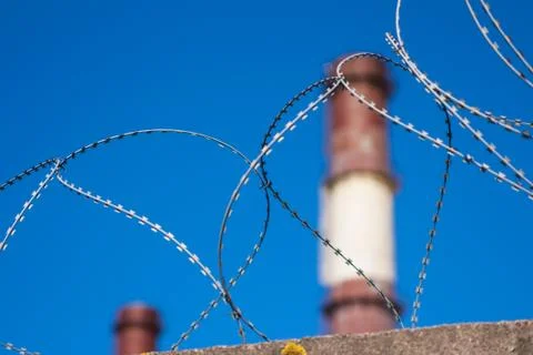 Barbed wire and pipe enterprises on the background of blue sky. Russia Saint  Stock Photos