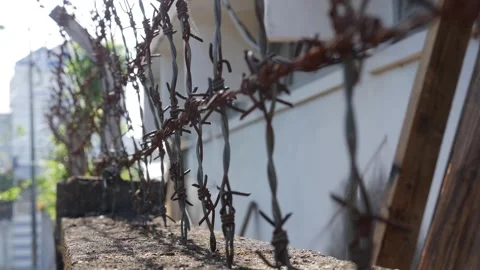 Barbed wire is attached to a fence structure mounted along a wall forming a 库存影片 334518375
