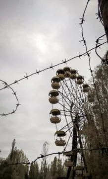 Barbed wire on the background of the ferris wheel in an abandoned amusement p Stock Photos