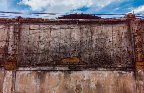 Barbed wire on background of old dirty concrete painted cracked wall. Copy space Stock Photos