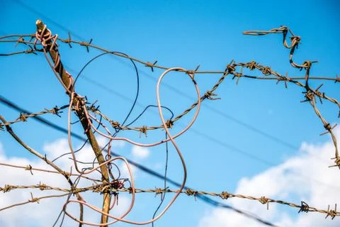 Barbed wire on the blue sky with clouds background Stock Photos