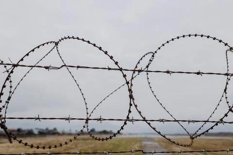 Barbed wire close-up against the background of a cloudy sky and take-off smog Stock Photos