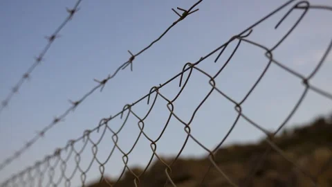 Barbed wire on fence, close-up. Border barbed wire fence with blue sky Stock Footage 283542459