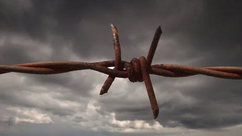 Barbed wire fence detail. Dramatic timelapse clouds in the background Видео 82291462