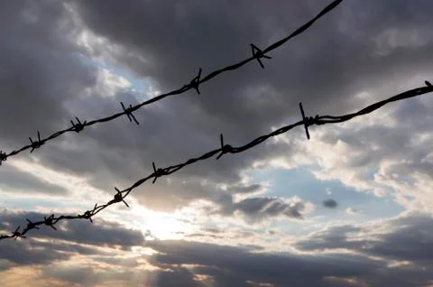 Barbed wire in front of cloudy sky Stock Photos