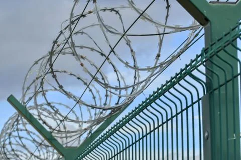 Barbed wire on a high-security building. Barbed wire and solid wire fencing Fotos de archivo