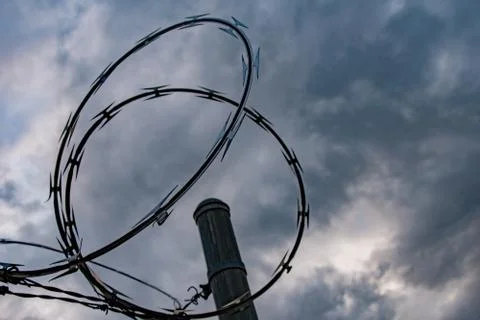 Barbed Wire Loops Against Cloudy Sky at Dusk Stock Photos