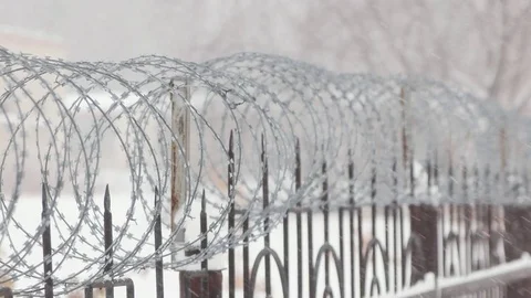 Barbed wire on metal fence with pointed rods. Snowing. Close. Stock Footage 70387853