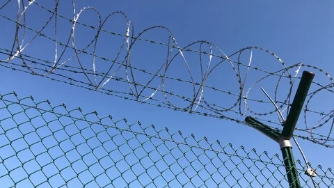 Barbed wire on net fence under blue sky Stock Footage 96531222