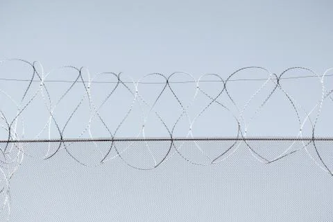 Barbed wire in the prison in the background of the grey sky Stock Photos