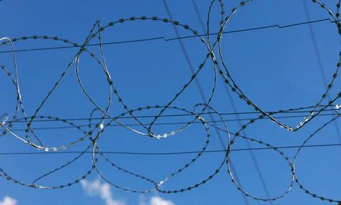 Barbed wire as a restriction . Against the backdrop of a bright blue sky Stock Photos