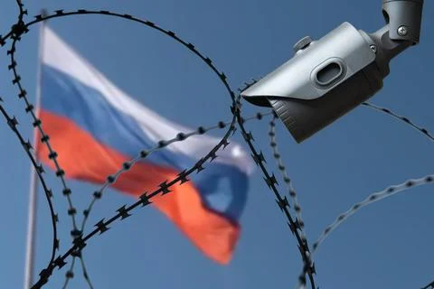 Barbed wire with a security camera on the background of the flag of Russia. Stock Photos