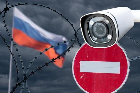 Barbed wire with a security camera on the background of the flag of Russia. Stock Photos